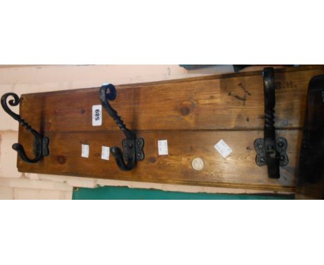 A vintage stained wood and iron wall mounted three hook coat rack with inset 6d coin