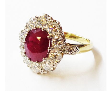 An unmarked high carat yellow metal ring, set with central 1.25ct. oval ruby within a ten stone diamond border with flanking 