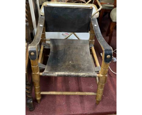 A vintage stained wood framed elbow chair with slung leather upholstery, set on bobbin turned supports