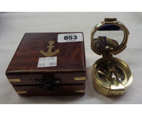 A modern brass compass in a brass inlaid box