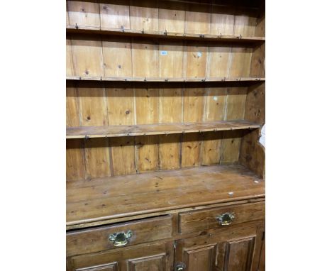 A 1.35m antique waxed pine two part dresser with three shelf open plate rack over a base with two frieze drawers and pair of 