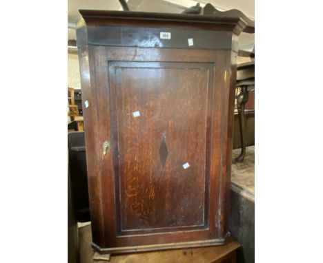 A 64cm late Georgian oak and mahogany strung wall mounted corner cabinet enclosed by a panelled door