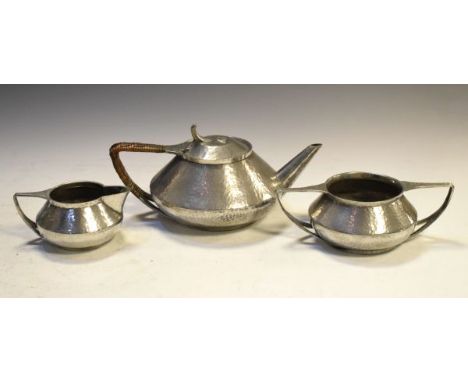 Art Nouveau style Roundhead planished pewter three piece tea service comprising: teapot, milk jug and two handed sugar basin 