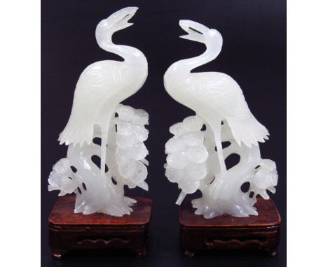 A pair of modern white jade carvings of herons, mounted on wooden stands, 21cm and 22cm high.