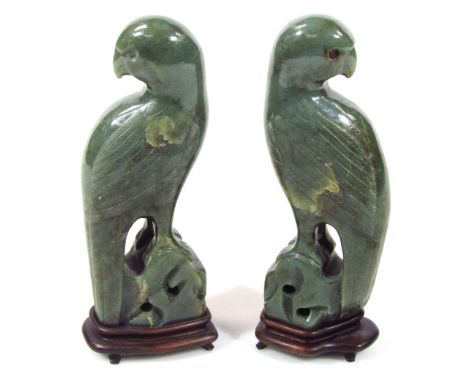A pair of polished jade carvings, of exotic birds on pierced bases and ebonised stands, 21cm high. (2)