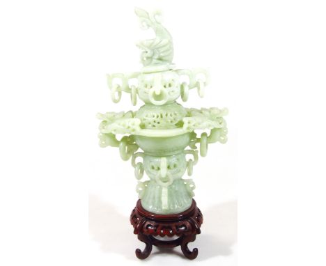 A Chinese light green jade style incense burner, of heavily elaborate design, with serpent and part pierced lid, above a comp