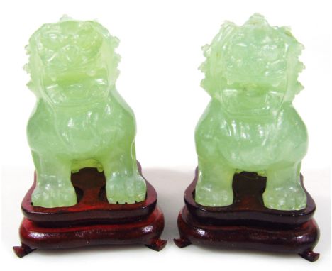 A pair of Chinese carved jade style Dogs of Fo, each modelled in a seated pose, 8.5cm high, with hardwood stands, in a fitted