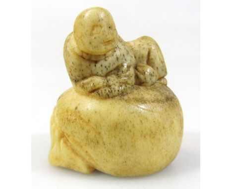 A Japanese carved nut netsuke, formed as a hotei in recumbent pose, on a part hollow shaped base, Taisho period, 4cm high. 