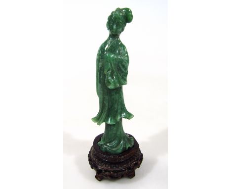 A dark green jade coloured figure of a geisha, standing in floral robes on a shaped carved base, 17cm high.