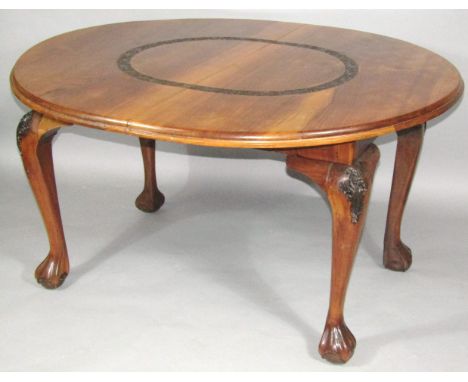 A late 19thC Chinese dining table, of oval outline with carved centre, on heavy cabriole supports terminating in stylised cla