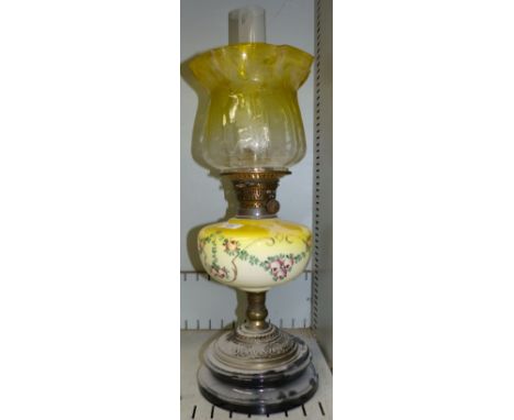 An oil lamp with yellow painted reservoir and yellow glass shade