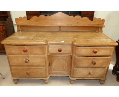 A Victorian pine dresser with single central cupboard, 7 drawers and shelf back