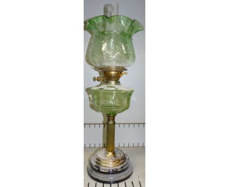 A glass oil lamp converted to electricity, with green reservoir and shade