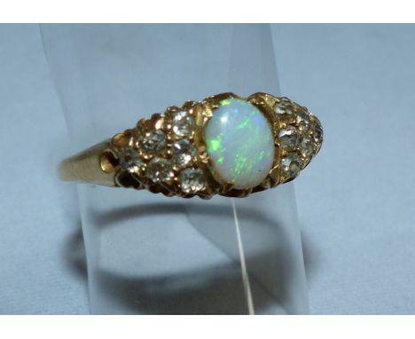 An 18 carat gold dress ring set centre opal surrounded by 12 small diamonds