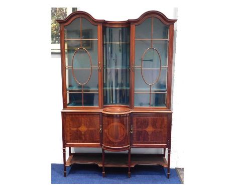 A two piece, Regency style Edwardian mahogany display cabinet with cylindrical convexed centre glass, cupboards & shelf under