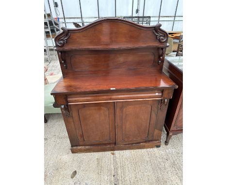 A VICTORIAN MAHOGANY CHIFFONIER WITH TWO DOORS TO BASE, RIASED BACK WITH FOLIATE CARVING + SHELF COMPLETE WITH FRIEZE DRAWER,
