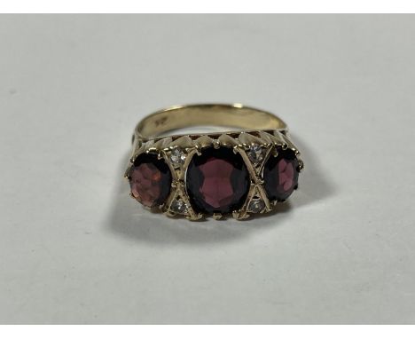 A 9 CARAT GOLD RING WITH THREE IN LINE GARNETS DIVIDED WITH DIAMONDS SIZE R/S 