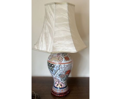 A CHINESE ENAMEL DESIGN TABLE LAMP WITH GEOMETRIC AND FLORAL DESIGNS, ON CARVED WOODEN BASE AND COMPLETE WITH SILK SHADE, HEI