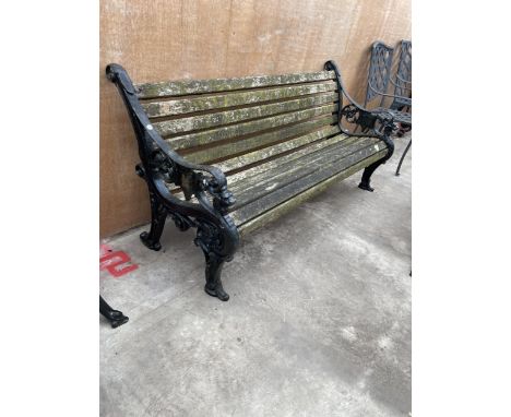 A HEAVY DUTY WOODEN SLATTED GARDEN BENCH WITH A PAIR OF HEAVILY DECORATED CAST IRON BENCH ENDS 