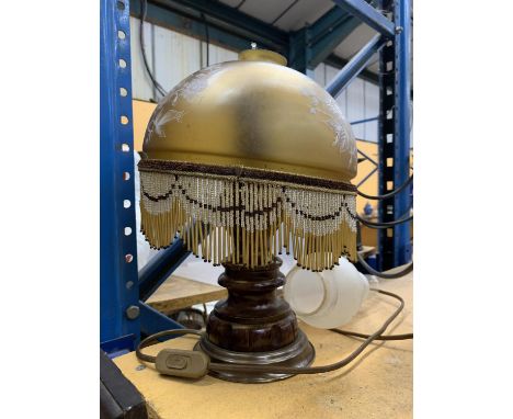 A VINTAGE TABLE LAMP WITH CARVED WOODEN BASE AND A GLASS LAMP SHADE WITH BEADING 