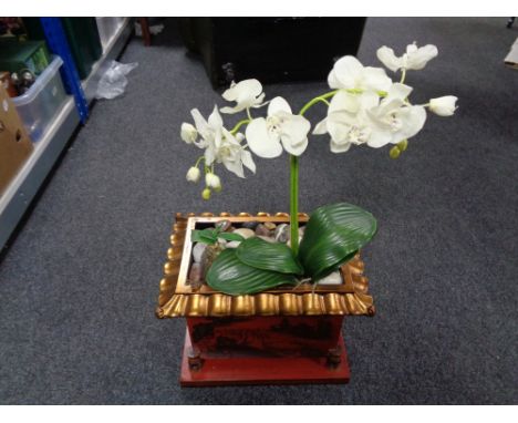 An oriental style planter containing artificial plants with pebbles. 