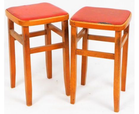 A pair of retro light wood stools, each with drop in leatherette seats on shaped square legs joined by upper horizontal stret