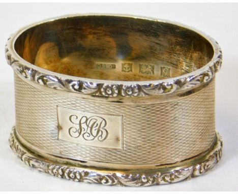 An Elizabeth II silver napkin ring, of oval form, partially engine turned with initialled cartouche and upper and lower flora