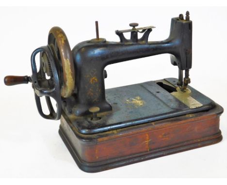 A late 19thC manual sewing machine, of small proportion, with metal body, wooden stand, wooden and metal articulated handle, 