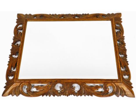 A 20thC oak mirror, with heavily carved scroll surround and bevelled glass, 110cm high, 88cm wide, 9cm deep.