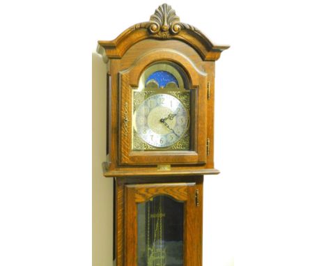 An oak finish longcase clock, with scroll and shell hood, arched glass door and panel base, 22cm arched dial and moon rolling