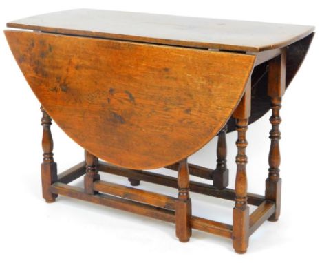 An 18thC style oak drop leaf gate leg table, on turned baluster supports joined by heavy block stretchers, with D end drop le
