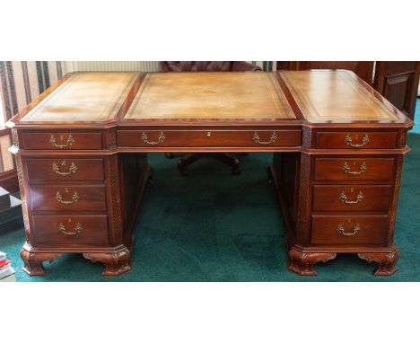 A mahogany partners pedestal desk of Chippendale design, inset tooled leather top, blind fret carved canted corners, 182cm by