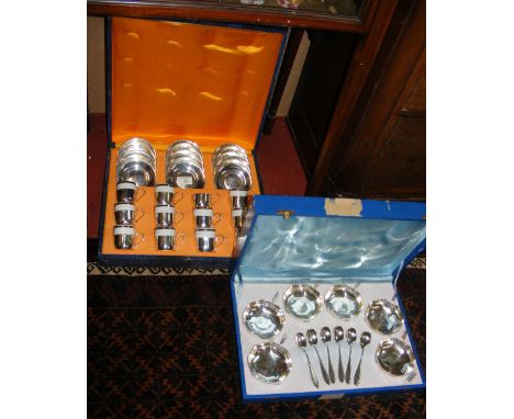 A cased set of twelve plated and ceramic coffee cans and saucers, together with one other of fruit bowls and spoons