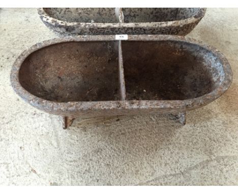 An oval two compartment cast iron pig trough