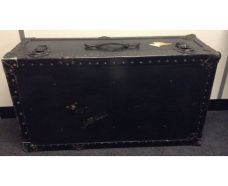 An early 20th century rectangular travelling trunk, the painted black planks with banded metal studs, leather carrying handle