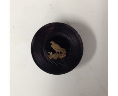 A 19th century lignum vitae circular snuff box, the screw on cover with a lacquer roundel decorated en piqué with a bird of p