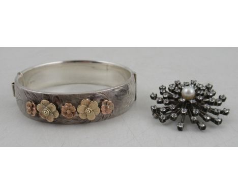 A silver hinged bangle, with applied gold flowers, together with a star burst brooch, set with pearl and a white stone&nbsp;