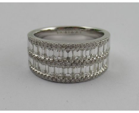 An 18k white gold diamond ring, channel set, the two rows of baguette cut diamonds highlighted with three rows of round brill