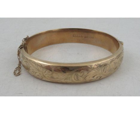 A 9ct hinged bangle, engrave to one half with a leafage scroll, weight 17g&nbsp;