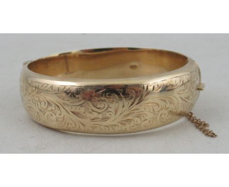 A 9ct hinged bangle, engraved to the front with a leafage scroll, weight 25.0g&nbsp;