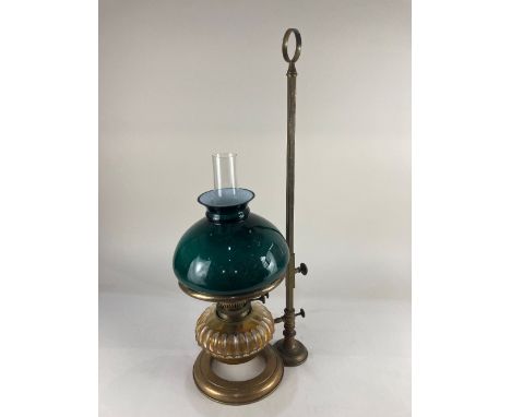 An adjustable brass oil table lamp circular stand and square brass rod with fluted glass oil well and green glass shade, 64cm