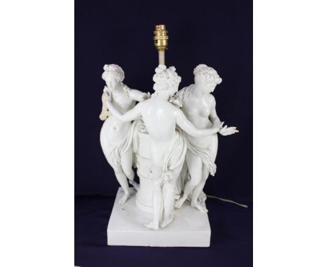 A white porcelain figural table lamp, in the form of the Three Graces around central column support, on integral rectangular 