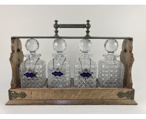 A Betjemann's patent brass mounted oak four decanter tantalus, containing four cut glass spirit decanters, with three blue en