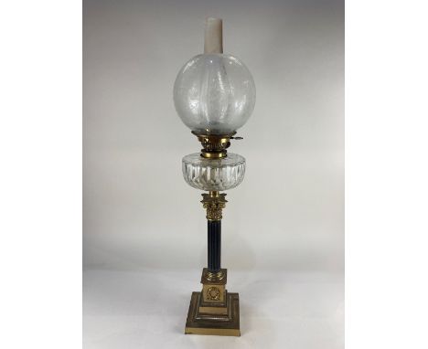 A brass Corinthian column table oil lamp with floral etched globe shade above fluted clear glass well on brass mounted fluted