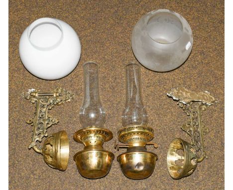 Two brass oil lamps on brackets with chimneys and shades, carved panel, five original and reproduction notices and postersCon