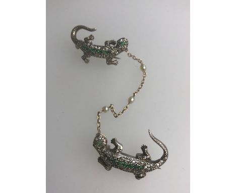 A Victorian brooch formed of a pair of yellow gold gem set lizards, the bodies set with rose cut diamonds, the spine and head