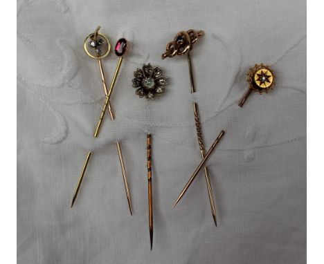 A three stone diamond stick pin together with four other stick pins