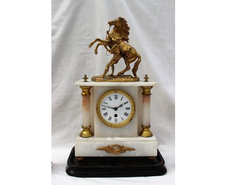 A 19th century gilt spelter and white marble mantle clock with marleys horse surmount, with twin pillars and a plinth on turn