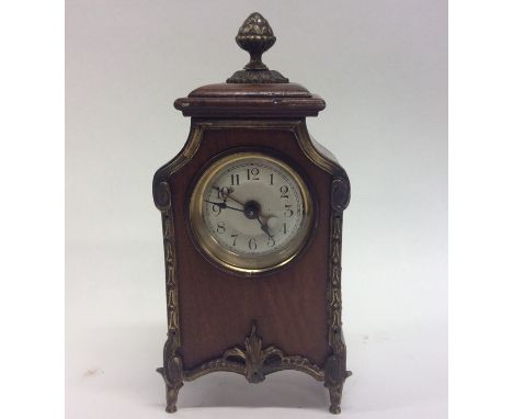 A small Edwardian brass mounted mantle clock decorated with swags and finial top. Approx. 18 cms high. Est. £50 - £80.