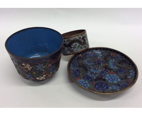 An unusual cloisonné cup and saucer decorated with bright flowers together with a napkin ring. Est. £25 - £35.